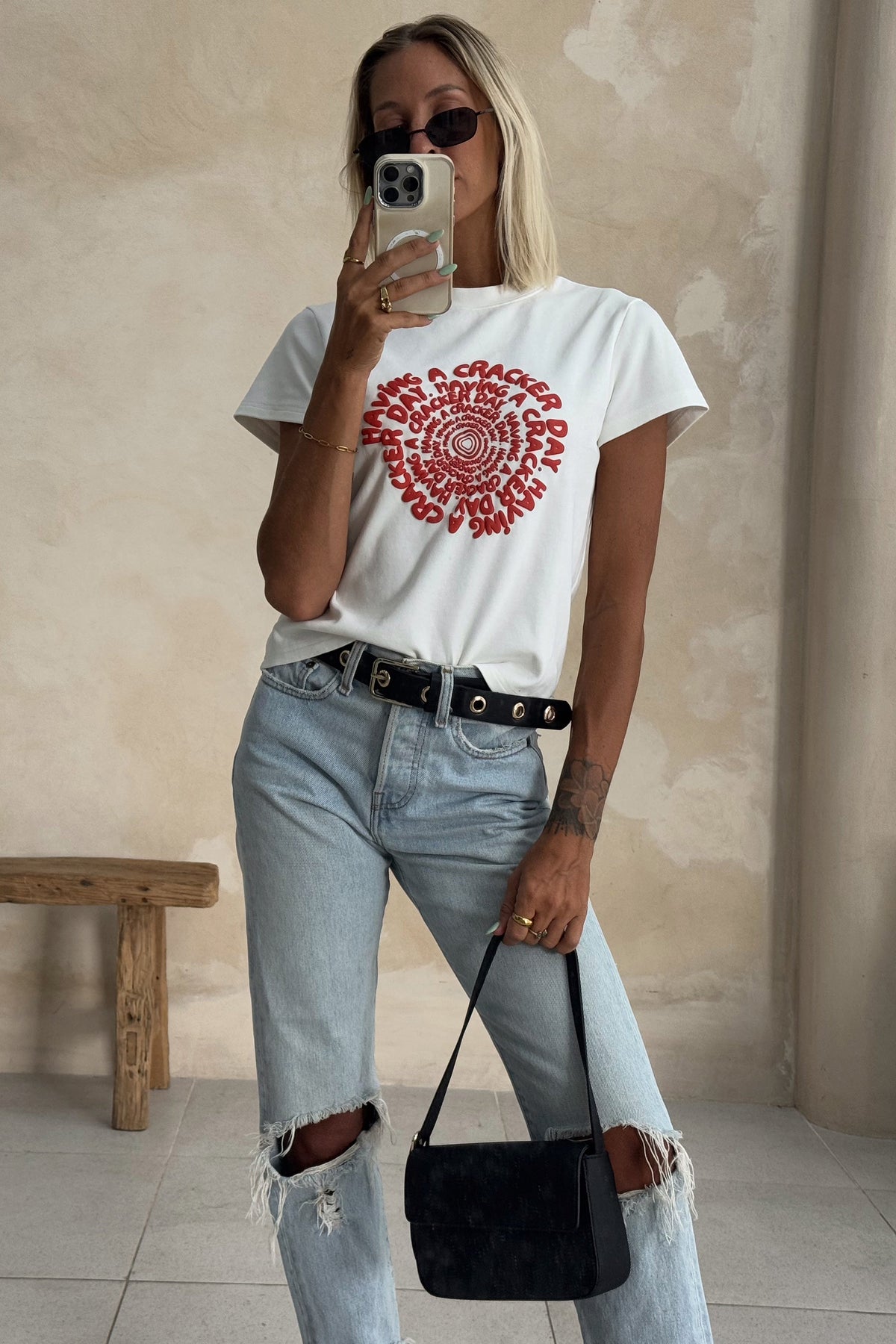 white baby tee styled with ripped denim jeans on a blonde woman
