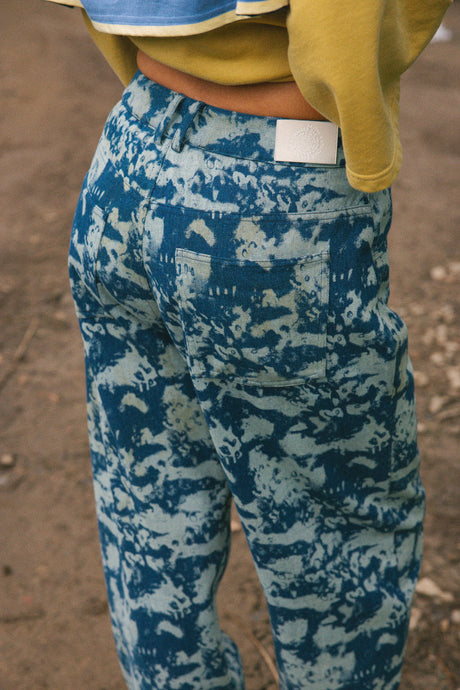Close-up back view of a person wearing blue and white camouflage cargo pants, with a yellow sweatshirt partially visible.