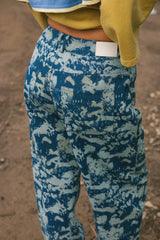 Close-up back view of a person wearing blue and white camouflage cargo pants, with a yellow sweatshirt partially visible.