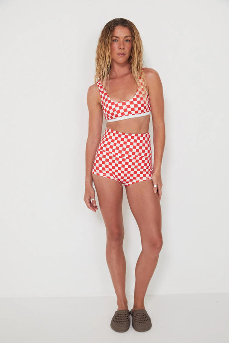 Woman wearing a red and white checkered bralette swim top and original betty bottoms on a white background