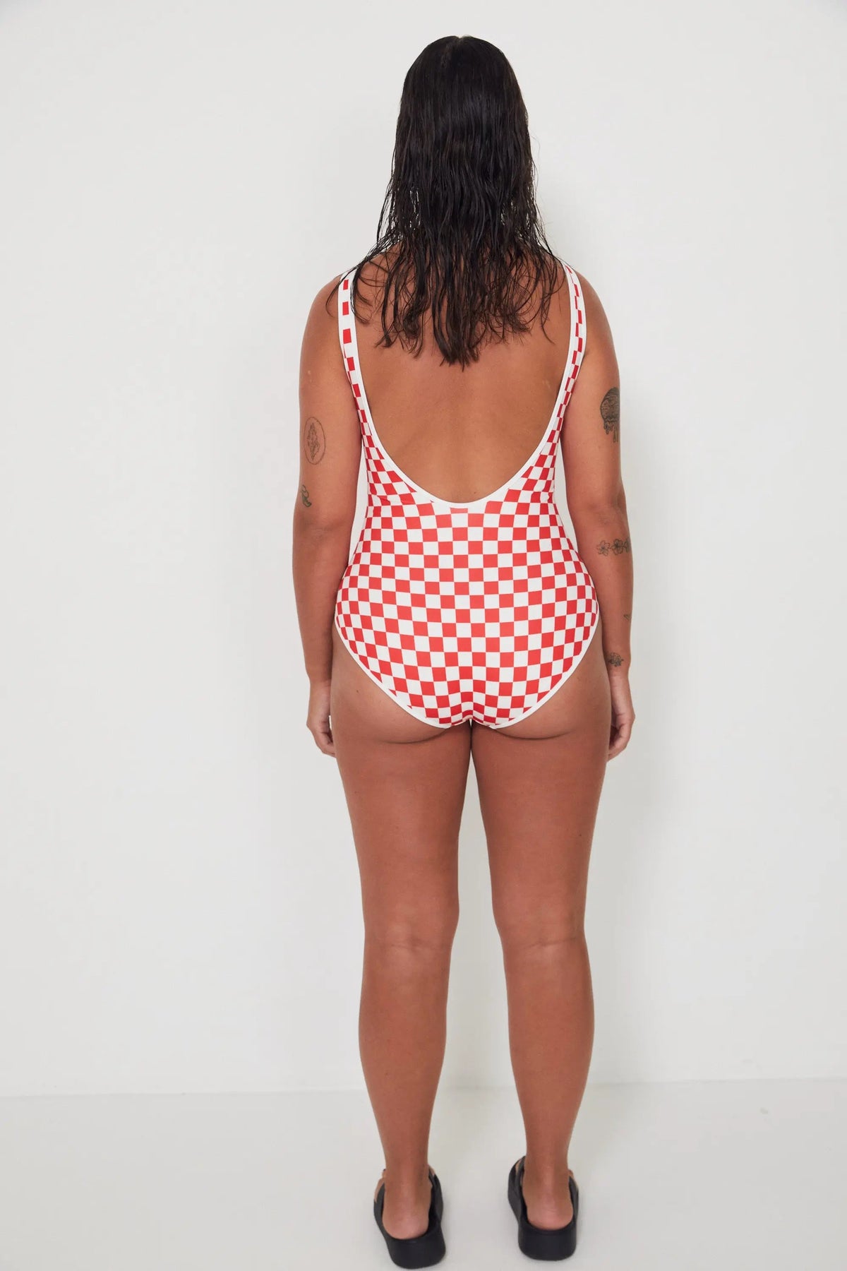 Person wearing a red and white checkered swimsuit against a white background