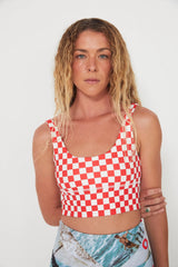 Woman wearing a red and white checkered punchy surf crop top against a white background