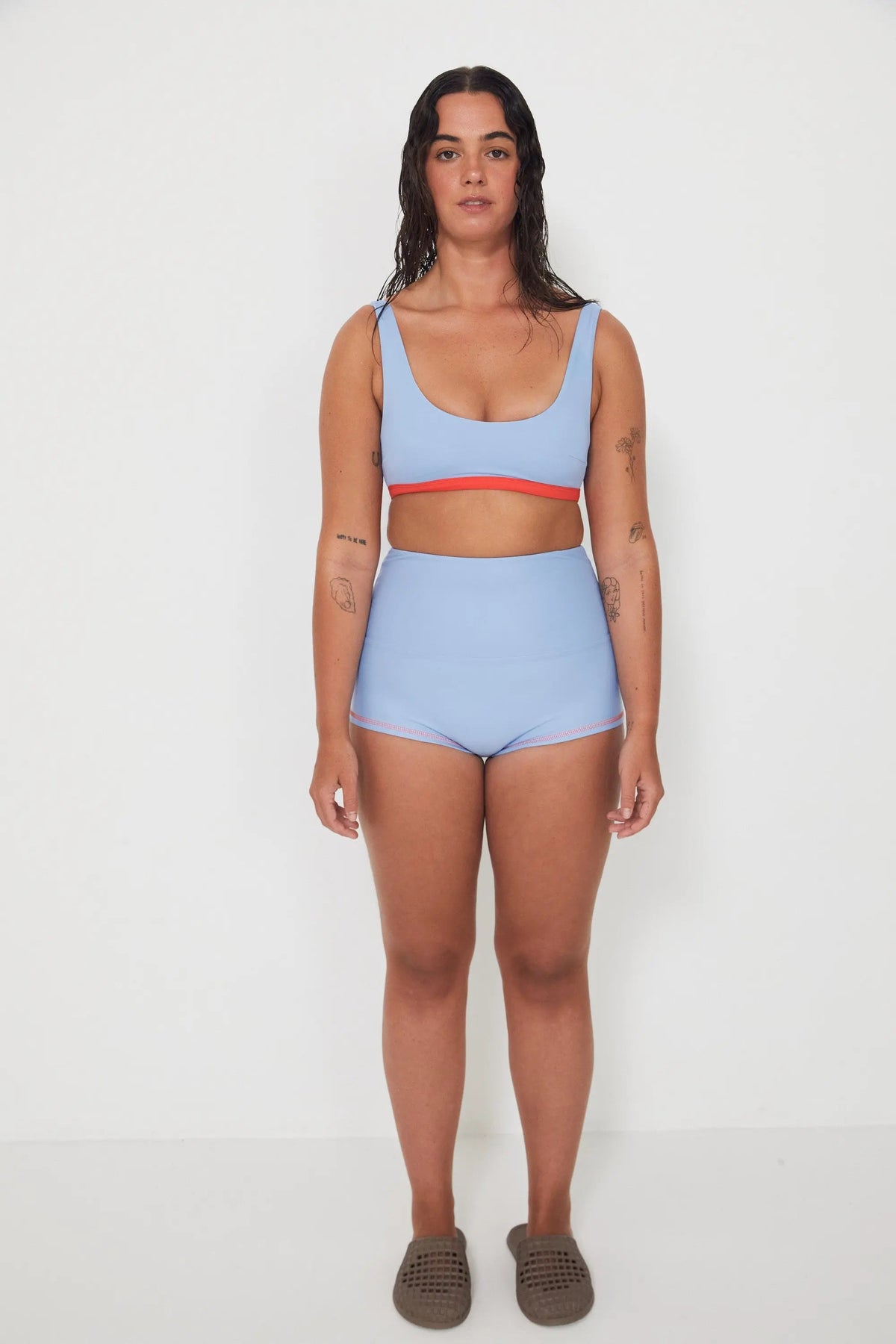Woman wearing a light blue bralette bikini and original betty bottoms with a white background