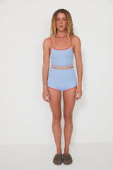 Woman wearing a light blue two-piece swimsuit with red trim on a white background
