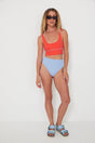 Woman wearing a red punchy surf top and light blue high-waisted drifer bikini bottoms on a white background