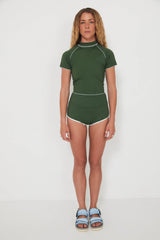 Woman wearing a green olive low rider rashguard and betty bottoms 2.0 with white trim on a plain background