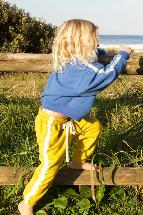 little boy wearing a blue oversized sweater by cracker day club playing at the beach