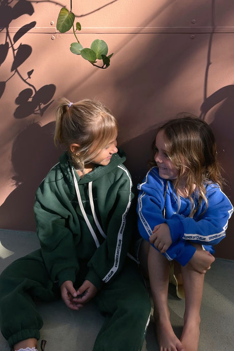 child wearing kids cloud racer sweater by cracker day club and talking to friend