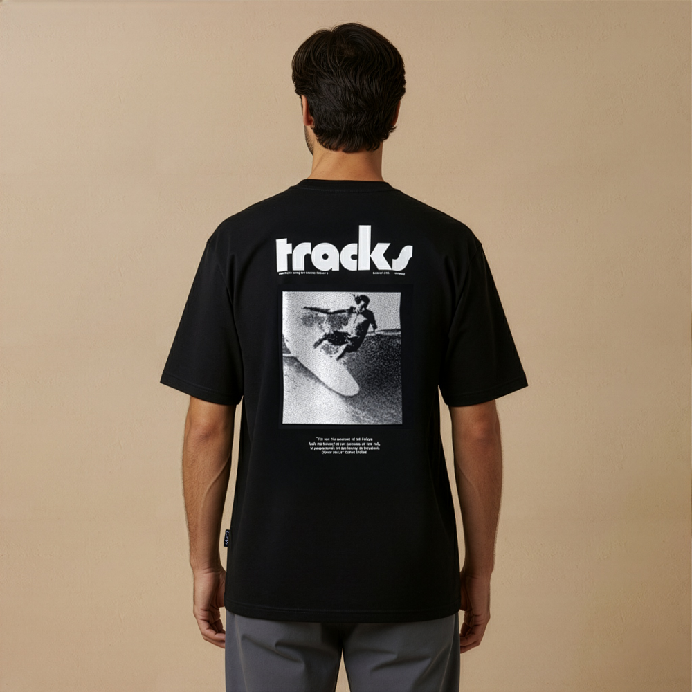Person wearing a black t-shirt with 'tracks' logo and graphic on beige background