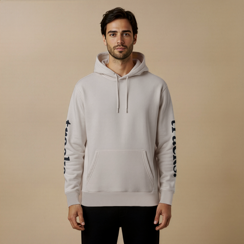 Man wearing a light gray hoodie with black text on sleeves against a beige background