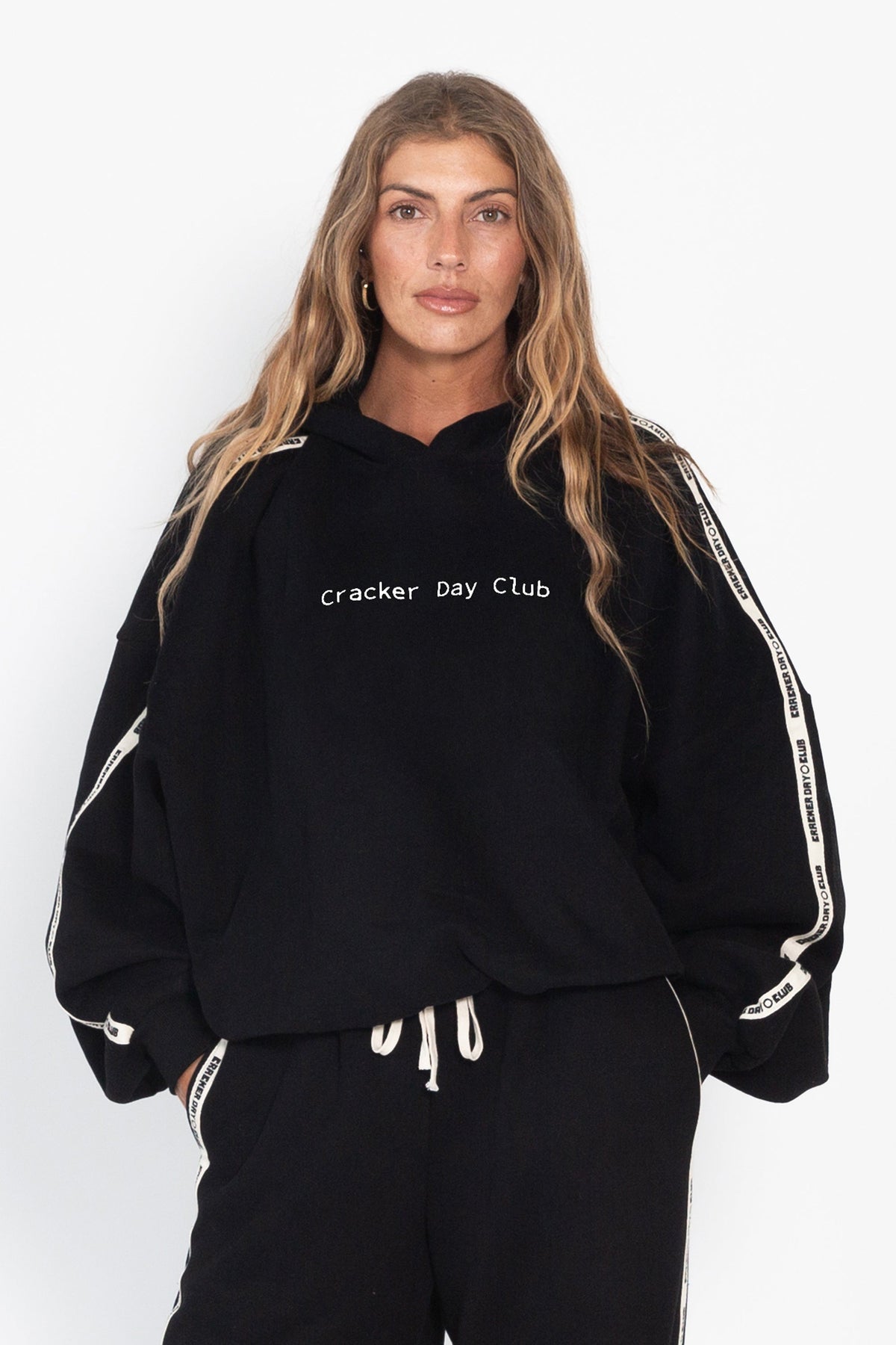 Person wearing a black hoodie with 'Cracker Day Club' text on a white background