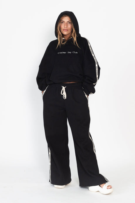 Person wearing a black tracksuit with white stripes on a white background