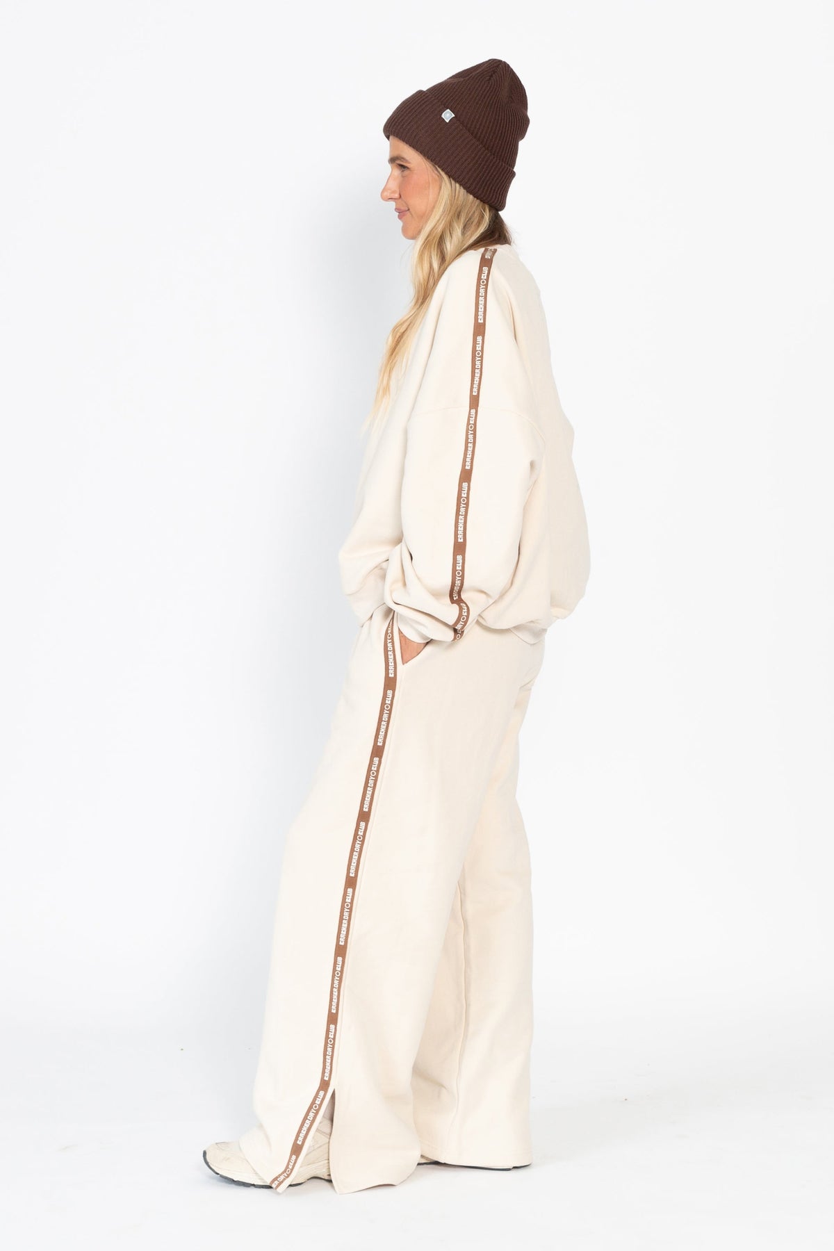 Person wearing a cream outfit with brown accents on a white background