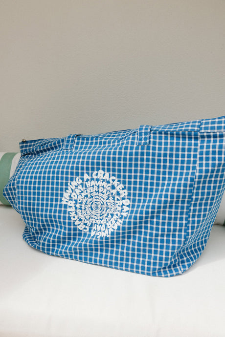 Blue checkered bag with a white having a cracker day design on a light gray background