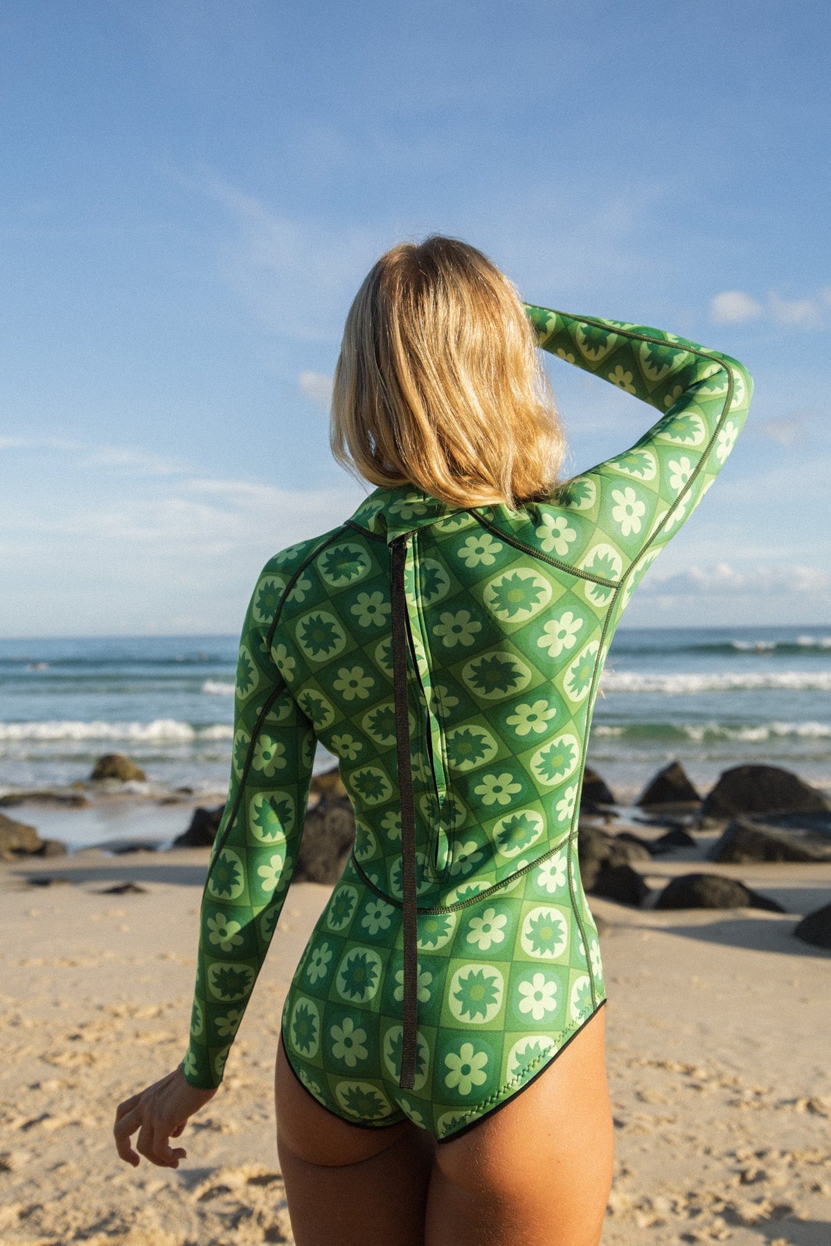 Person wearing a green patterned swimsuit on a beach