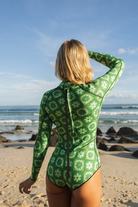 Person wearing a green patterned swimsuit on a beach